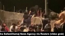 Cu riscul vieții, oamenii încearcă să sară gardul ca să pătrundă în perimetrul aeroportului din Kabul, Afganistan, 21 august 2021.