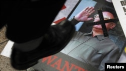 Сүрөттө: түштүк кореялык демонстрант Түндүк Кореянын жол башчысынын сүрөтүн тепсеп жатат, 25-май, 2010-жыл.