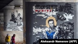 Járókelők Eva Buszevics Navalnijt ábrázoló graffitije előtt Moszkva közelében, 2021. április 6-án. A bebörtönzött ellenzéki vezetőt ábrázoló kép ihletője Mihail Vrubel orosz festő 1890-ben készült képe, Az ülő démon volt