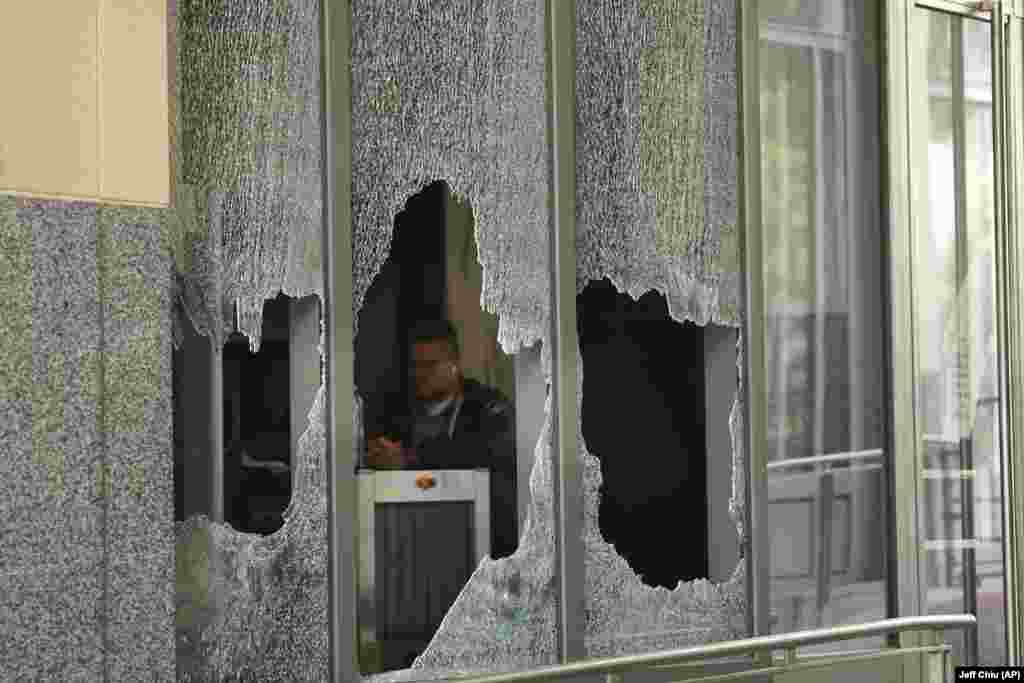 Маж седи зад скршено стакло од прозорецот во федералната зграда Роналд В. Делумс во Оукланд, Калифорнија&nbsp;
