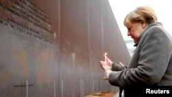 Канцлер Німеччини Анґела Меркель запалює свічку перед меморіалом розділеному місту і жертвам комуністичної тиранії, Берлін, 9 листопада 2019 року