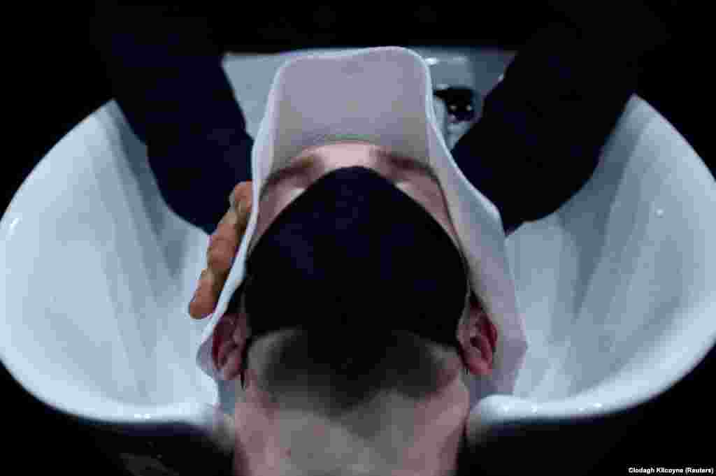 Egy férfi élvezi, hogy szakértő kezekben lehet újra a feje, azaz hajkoronája ennél az írországi borbélynál.