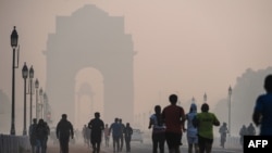 Kocogók a délelőtti szmogban Új-Delhiben 2015. november 15-én