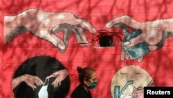 Женщина на фоне граффити на коронавирусную тему в Мумбаи.