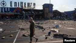 Un bărbat trece pe lângă un centru comercial care a fost lovit de o rachetă rusă în orașul Kamianske, din regiunea Dnipro, Ucraina, pe 26 iulie.