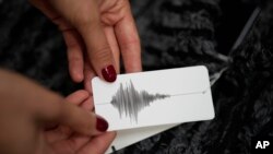 Ksenia Schnaider, ukrán divattervező egy olyan címkét mutat, amelyet ha beolvasnak a telefonjukon a vásárlók a légiriadó sziréna hangját hallhatják a telefonjukon, az angliai Haywards Heath-ben, West Sussexben, 2023. szeptember 14-én