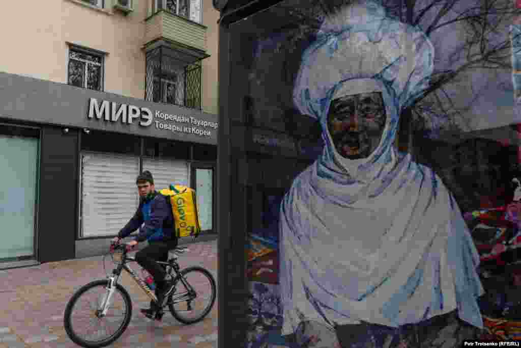 Сотрудник компании по доставке еды на дом едет по одной из центральных улиц Алматы.