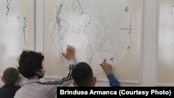 Copiii de la Școala Iris din Timișoara pentru copii cu deficiențe de vedere examinează tactil lucrările Alinei Cioară