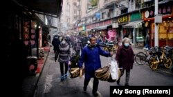 Disa persona duke ecur rrugëve të Vuhanit me maska për mbrojtje kundër koronavirusit. Fotografi nga arkivi.