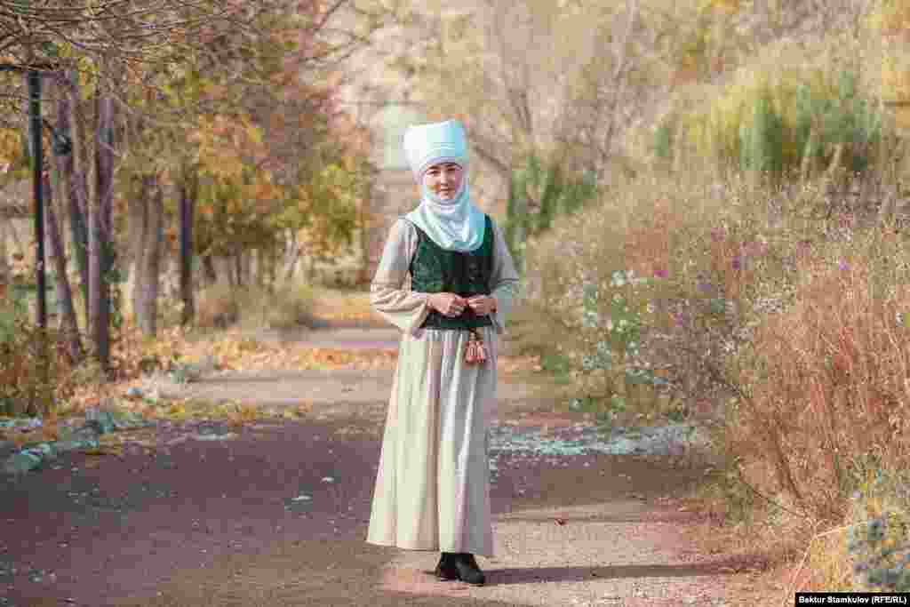 Элечек оронуп, улуттук кийим кийген айым.