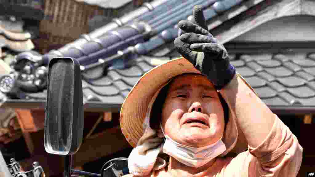 Биринчи күчтүү жер титирөө бейшемби күнү кечинде болгон. Сүрөттө: Көзүнө жаш алган аял Кумамотодогу Машки шаарында талкаланган үйү тууралуу айтып жатат. &nbsp;