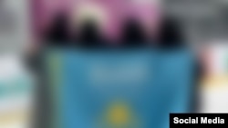 Никабчан кыздар араб жазуусу түшүрүлгөн Казакстандын желегин кармап турушат. (Социалдык тармактардан алынган сүрөт).