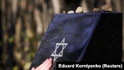 Një grua prek monumentin që përkujton viktimat e Holokaustit në Stavropol të Rusisë më 15 nëntor 2017. 