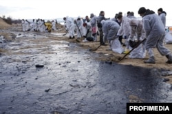 Волонтери прибирають просочений нафтою пляжний пісок поблизу чорноморського курортного міста Анапа, грудень 2024 року