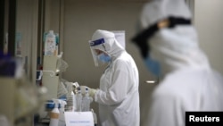 Stafi shëndetësor me uniformë mbrojtëse ndaj sëmundjeve infektive.