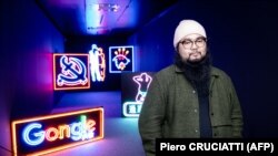 Kineski disidentski umetnik Badiukao ispred serije njegovih umetničkih radova s neonskim svetlima posvećenih Hongkongu, na izložbi u Breši, Italiji, u novembru 2021.