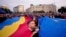 Учасники акції тримають великі прапори Румунії та Євроcоюзу під час мітингу напередодні переголосування президентських виборів у Бухаресті, Румунія, 9 травня 2025 року