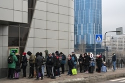 Oameni stau la coadă pentru a retrage bani de la un bancomat din Kiev, în dimineața zilei de 24 februarie 2022.