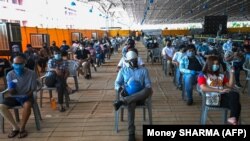 Njerëzit duke pritur që të vaksinohen në një qendër vaksinimi në Indi. 