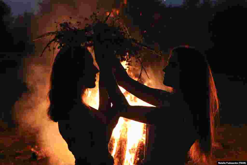 Дівчата одягають на голову вінки біля купальського&nbsp; багаття. Під час святкування Івана Купала на березі річки Прип&#39;ять. Гомельська область Білорусі, 6 липня