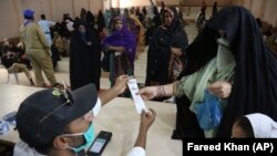 People receive cash vouchers under the government Ehsaas Emergency Cash Programme for families in need during a government-imposed nationwide lockdown to help contain the spread of the coronavirus, in Karachi on April 14.