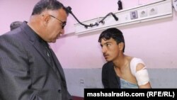 Khost Governor Mohammad Halim Fidai talks with an one of those injured on March 3.