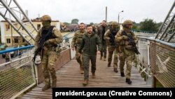 უკრაინის პრეზიდენტი ვოლოდიმირ ზელენსკი (ცენტრი) სამხედრო პერსონალთან ერთად ქალაქ იზიუმში, რომელიც ახლახან გაათავისუფლეს უკრაინის შეიარაღებულმა ძალებმა რუსი სამხედროებისგან. იზიუმი, ხარკოვის რეგიონი, 2022 წლის 14 სექტემბერი.