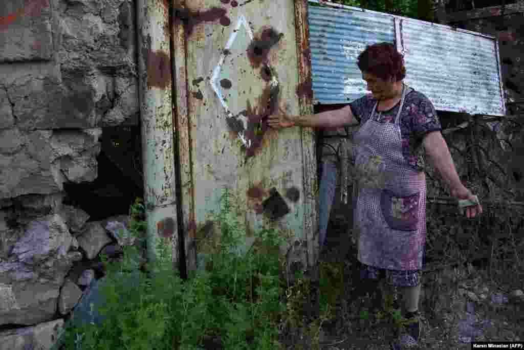 Женщина показывает следы от обстрела в своем дворе. Село Айгепар, Армения