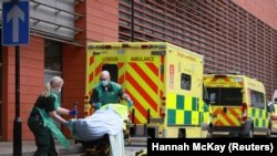 Коронавируска чалдыккан бейтапты көтөрүп бараткан медкызматкерлер. Лондон. 26-январь, 2021-жыл. 