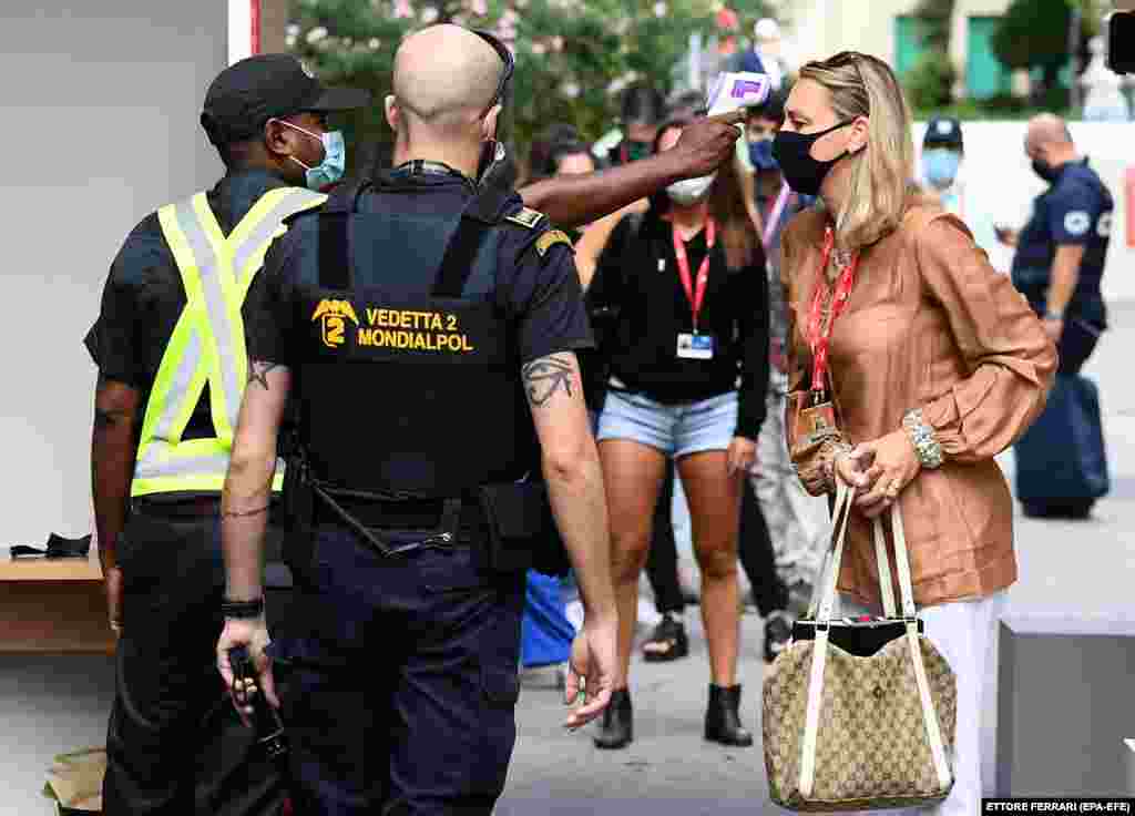 Një zyrtar policor kontrollon temperaturën e një gruaje, në hyrje të Fesitvalit të Venecias. Autoritetet kanë ndërmarra masa të ndryshme për të zvogëluar përhapjen e koronavirusit.