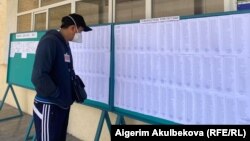 Шайлоо тилкесиндеги маалымат тактасынан тизме окуп турган жаран. Бишкек, 11-апрель, 2021-жыл.
