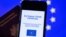 A picture taken on June 16, 2021 in Brussels shows a passeport behind a mobile phone whose screen bears a EU Digital Covid certificate. 
