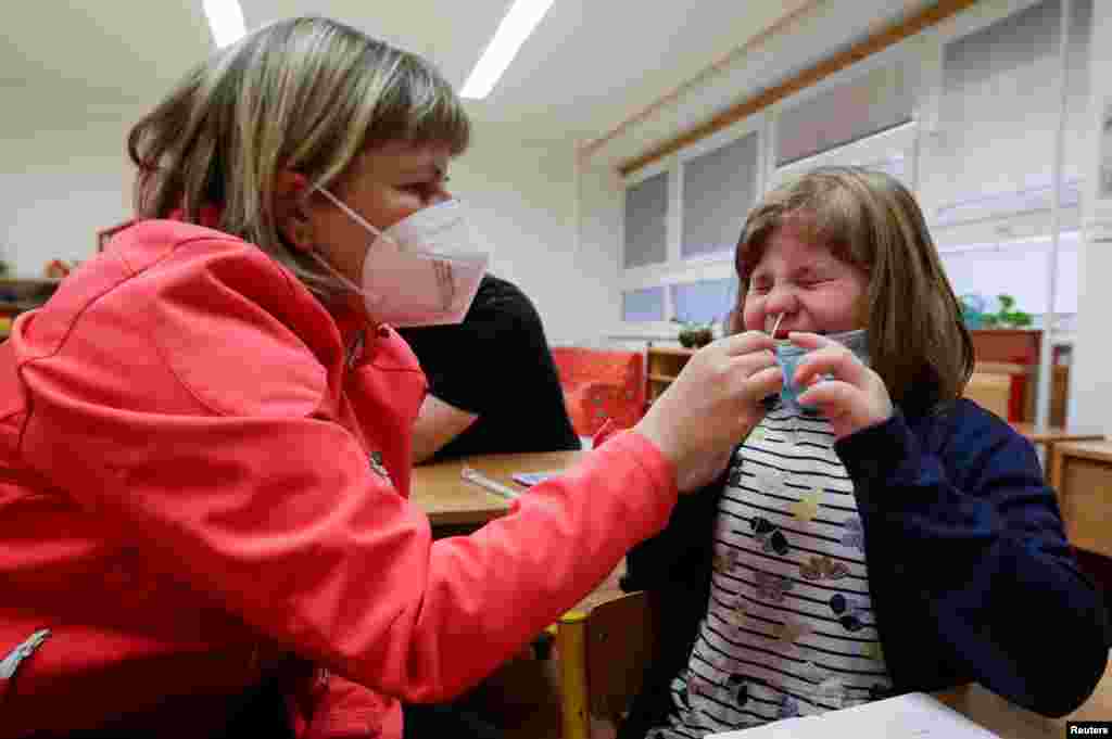 Csehországban is lazítottak. Ebben a prágai általános iskolában épp egy szülő vesz mintát antigén-teszthez az egyik tanulótól.