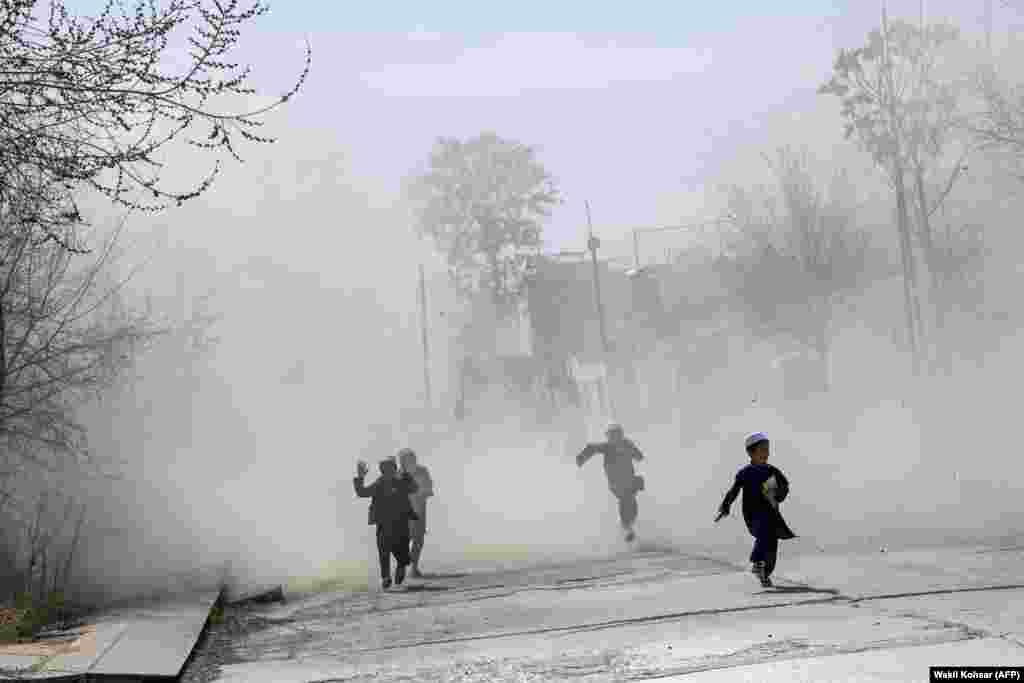 کودکان افغان در حال دویدن در میان گردوغبار برخاسته از فرود بالگرد نظامی در منطقه سبز کابل.