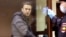 Russian opposition leader Aleksei Navalny, charged with defaming a World War II veteran, looks out from inside a glass cell during a court hearing in Moscow on February 5.