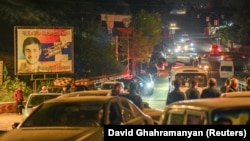 Etnici armeni din capitala regiunii Nagorno-Karabah părăsesc orașul cu mașinile, în urma unei operațiuni militare a forțelor armate azere, 24 septembrie 2023. Un panou din fundal afișează un steag al Rusiei și pe președintele Vladimir Putin.