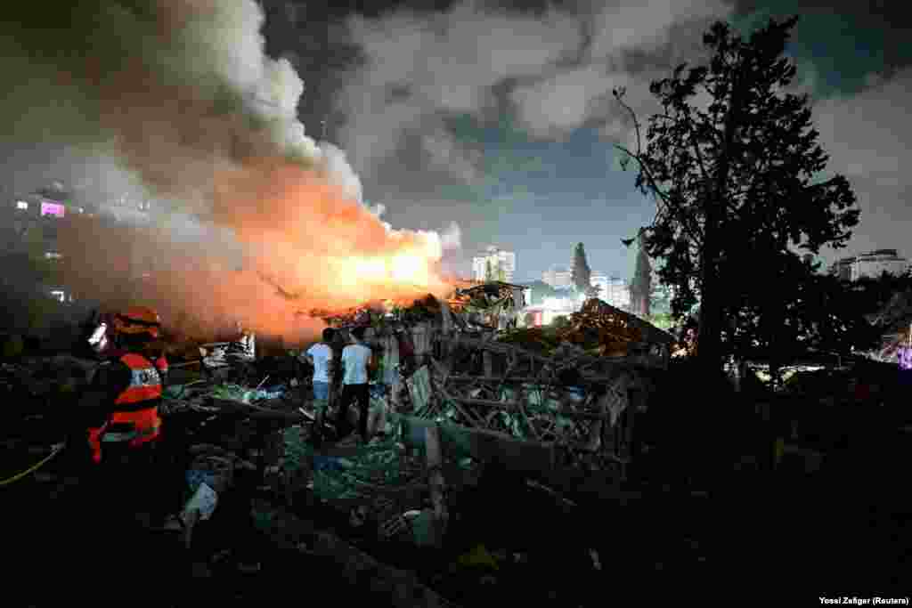 Banorë duke shikuar zjarrin në një vend të sulmuar nga Irani, në Izraelin qendror, më 15 qershor.