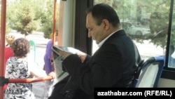 Awtobusda gazet okap oturan bir ýolagçy