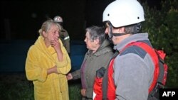 Salvatorii ucraineni îi ajută pe locuitorii unei clădiri rezidențiale avariate după un atac cu drone asupra orașului Harkov, în noaptea de 2 spre 3 mai. 