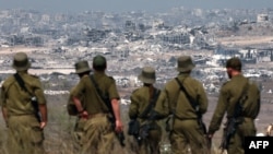 آرشیف، سربازان اردوی اسرائیل در مرز با قلمرو فلسطین به ساختمان‌های ویران شده در نوار غزه نگاه می‌کنند.