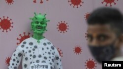 Индиялык жаран COVID-19 илдетин элестеткен тулдун жанында турат. Мумбай (мурдагы Бомбей), Индия. 2020-жылдын 30-декабры. 