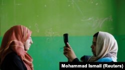 Alegătoare si funcționară electorală folosind un dispozitiv biometric in alegerile prezidențiale din Afganistan.