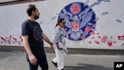 زوج جوانی در حال عبور از مقابل سفارت سابق آمریکا در تهران