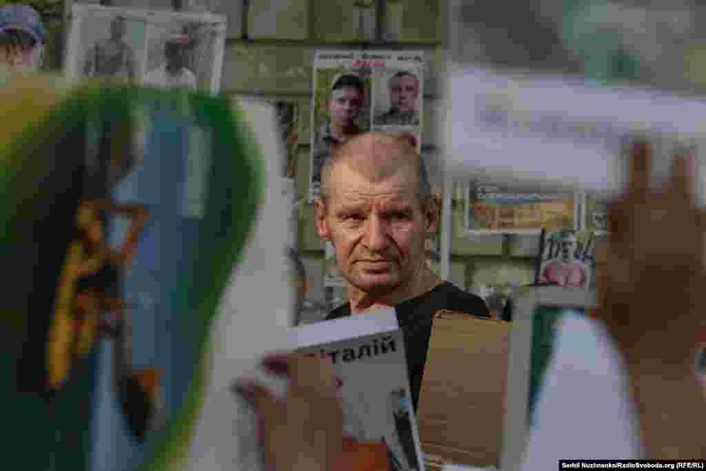 Український військовий, який повернувся з полону РФ, дивиться на фото, які йому показують родичі військовополонених та зниклих безвісти