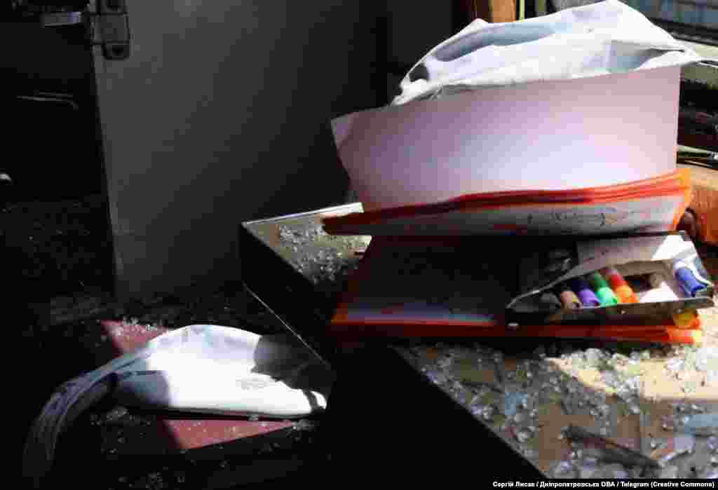 Дитячий зошит та пенал з фломастерами поміж уламків скла пошкодженого через російську атаку вікна потяга, Дніпропетровщина, 24 червня 2025 року