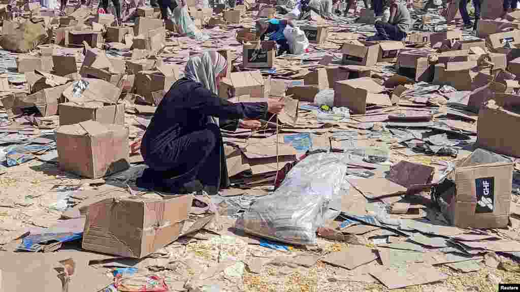 Женщина рядом с коробками Гуманитарного фонда Газы, поддерживаемого США, когда палестинцы собирают остатки гуманитарных грузов из распределительного центра Гуманитарного фонда Газы в Рафахе, на юге сектора Газа, 5 июня 2025 года. REUTERS/Stringer