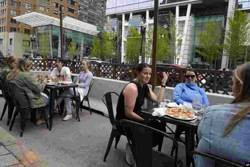 Clienții unui restaurant conversează și iau masa fără măști, duminică, 2 mai 2021, în Boston. În Massachusetts începând de vineri, 30 aprilie 2021, măștile sunt necesare în aer liber numai atunci când nu este posibil să se mențină o distanță de aproximativ 1,5 metri între persoane (Foto AP / Steven Senne)