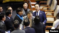 Parlamentarul PPP Kim Sang-wook (în centru) este felicitat de parlamentarii democrați după ce a votat pentru punerea sub acuzare a președintelui - primul, din partidul său. 