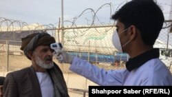 An Afghan health worker checks the temperature of people returning from Iran at the Islam Qalah border crossing on February 23.