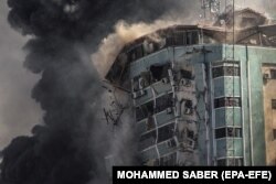 Füst száll fel 2021. május 15-én, amikor egy izraeli légicsapás nyomán összeomlik az Al-Dzsalaa toronyház, amely lakásoknak és több médiaszervezetnek, köztük az Associated Pressnek és az Al Jazeerának adott otthont Gáza városában.